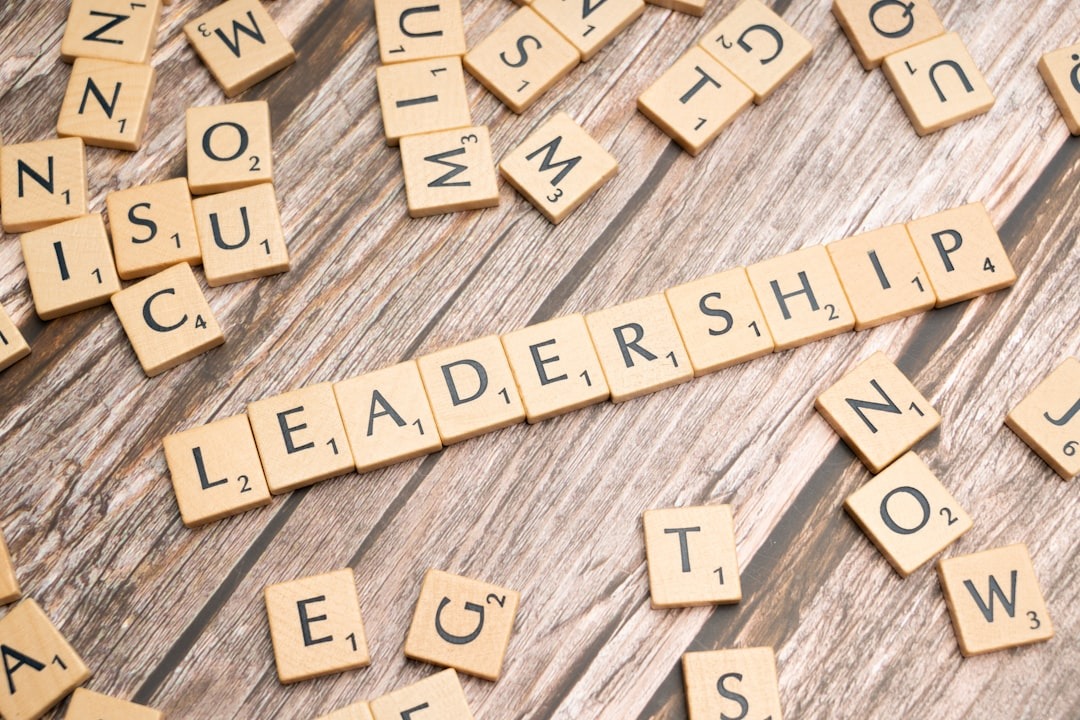 Scrabble tiles spell out 'LEADERSHIP' on a wooden table.